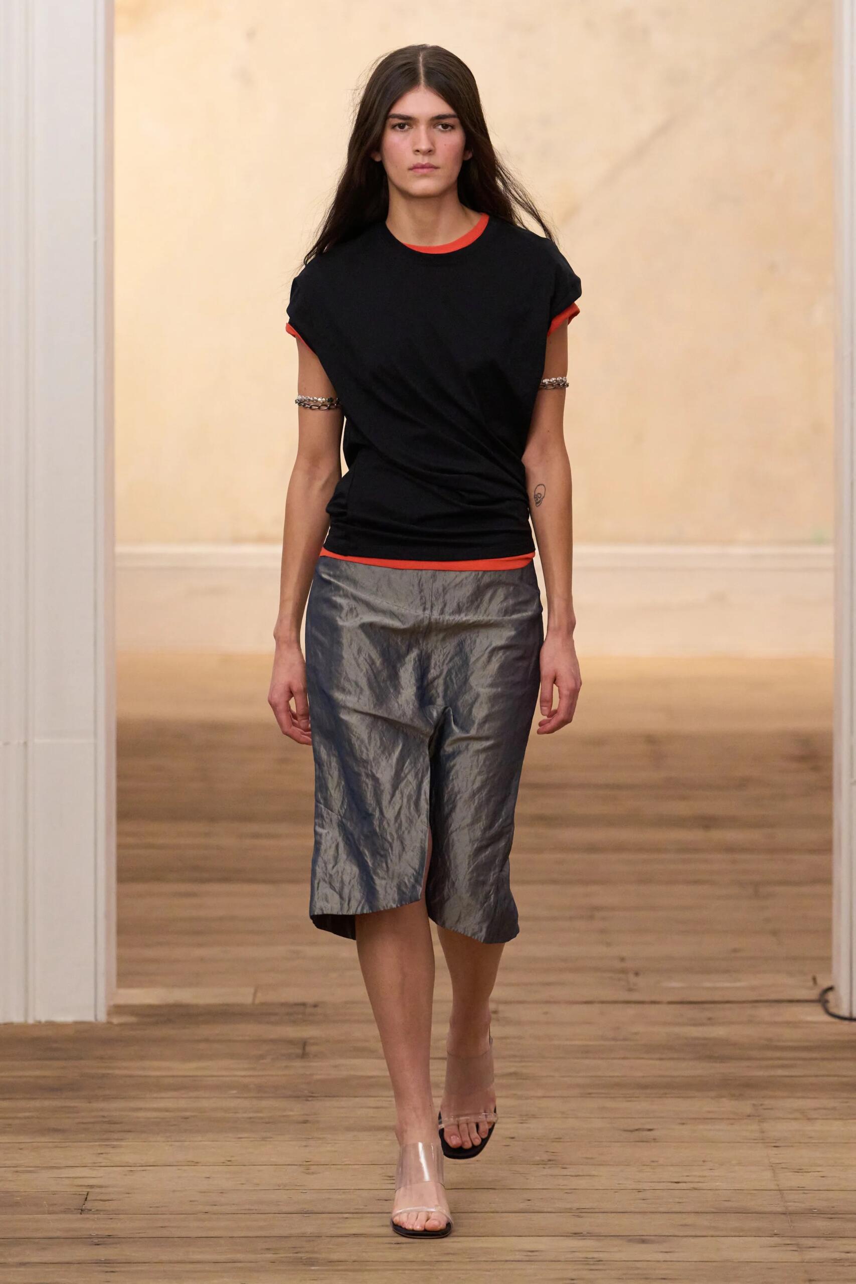 Eckhaus Latta printemps-été 2027, look 1 : T-shirt noir torsadé et jupe crayon métallisée froissée.