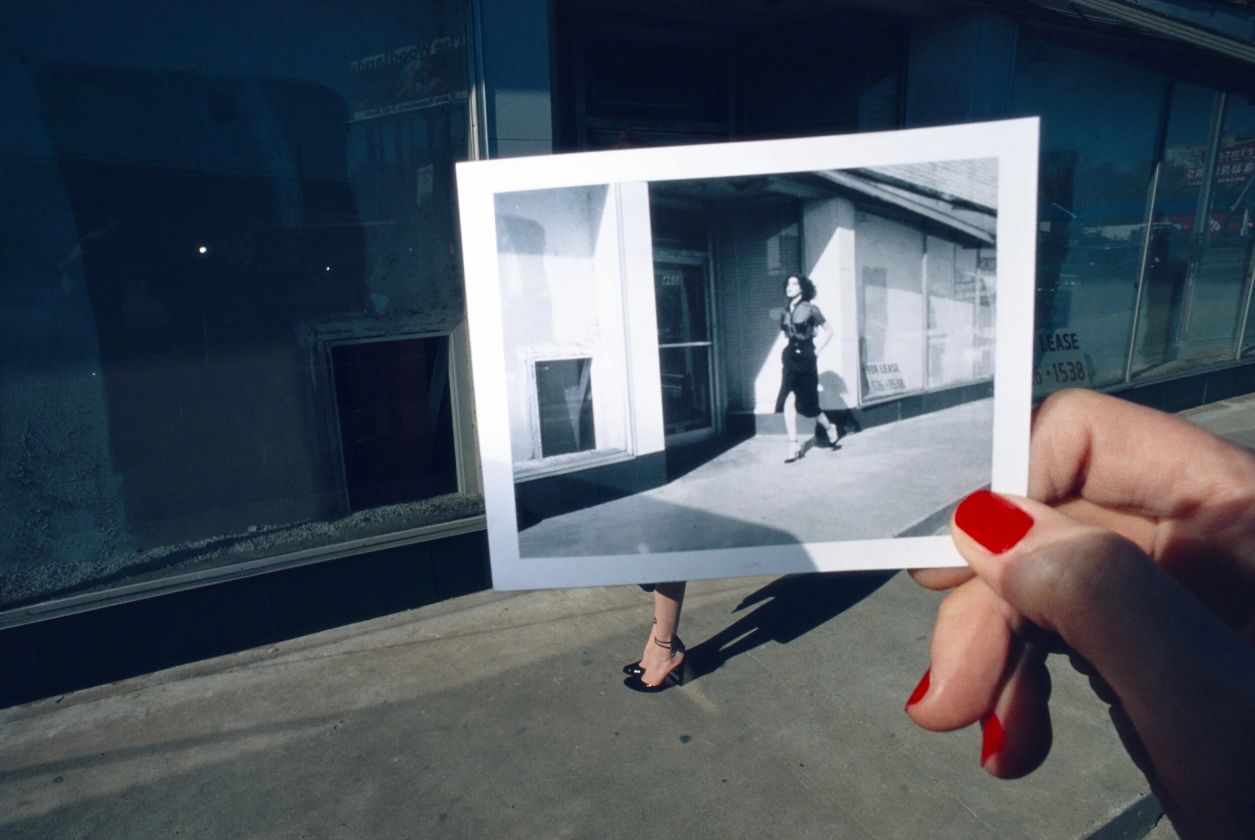 Guy Bourdin for Charles Jourdan: a hand holds a photograph over the street scene it depicts.