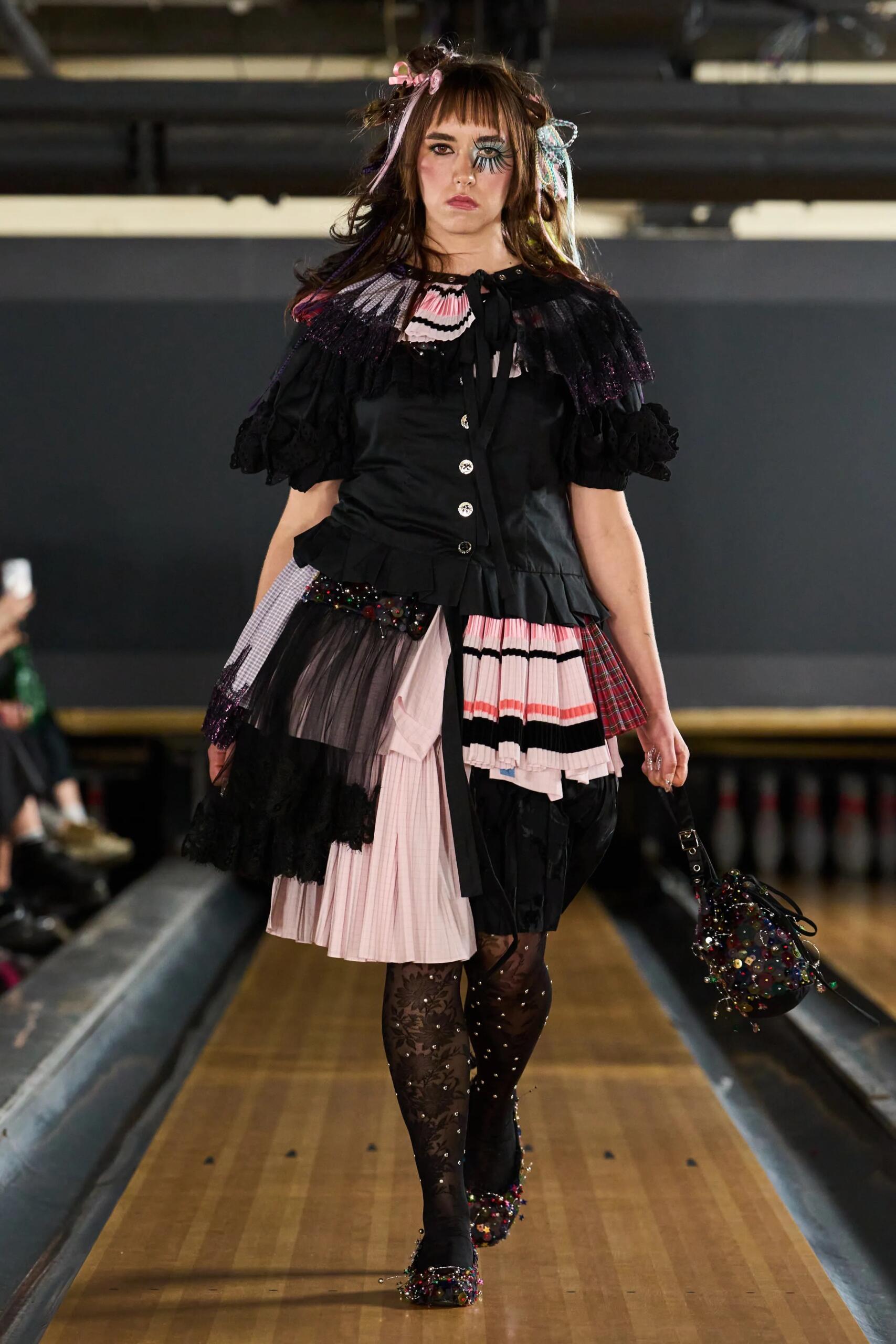 Chopova Lowena printemps-été 2027, look 1 : ensemble noir et rose plissé sur une piste de bowling.
